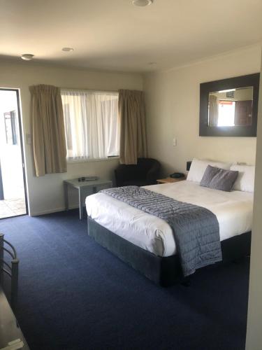a hotel room with a large bed and a chair at Claremonte Motor Lodge in Hastings