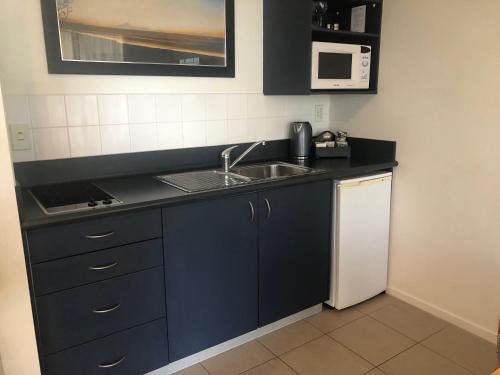 a small kitchen with a sink and a microwave at Claremonte Motor Lodge in Hastings