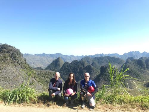 a group of three people sitting on top of a mountain at Meo Vac Cosy Hostel in Mèo Vạc