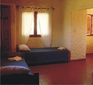Schlafzimmer mit einem Bett und einem Fenster mit Vorhängen in der Unterkunft Cabañas Achalay in Santa María