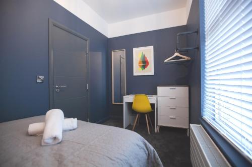 a bedroom with a bed and a desk with a yellow chair at Yellow Hive Boutique Stay Apt 1 in Belfast