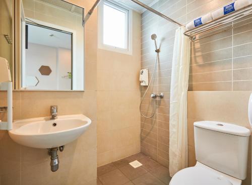 uma casa de banho com um lavatório, um WC e um espelho. em ibis budget Singapore Imperial em Singapura