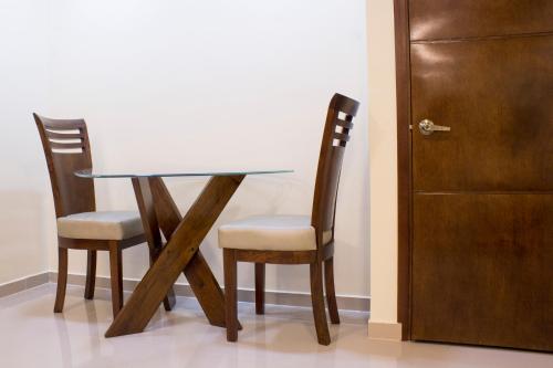 a glass table and two chairs next to a door at APARTAHOTEL LION in Tuluá