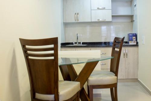 a kitchen with a glass table and two chairs at APARTAHOTEL LION in Tuluá