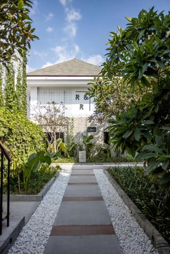 a garden with a walkway in front of a building at Rhythm & Rumble Hostel in Canggu