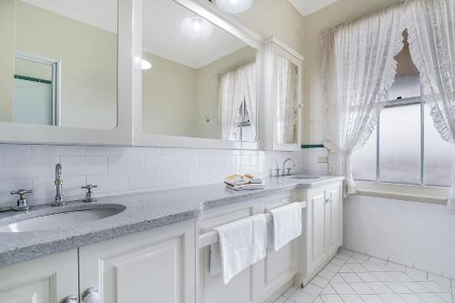 a white bathroom with a sink and a window at Ballina Heritage Inn in Ballina