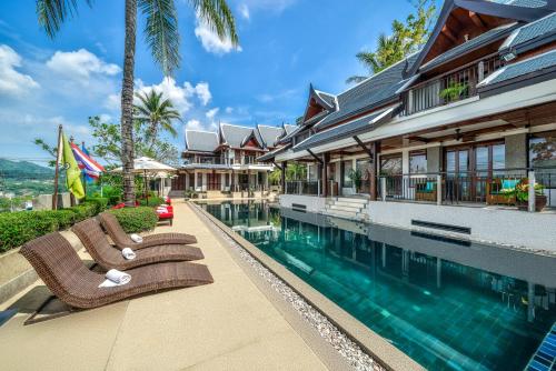 a swimming pool with two lounge chairs next to a house at Baan Yin Dee Boutique Resort Phuket - SHA Plus in Patong Beach