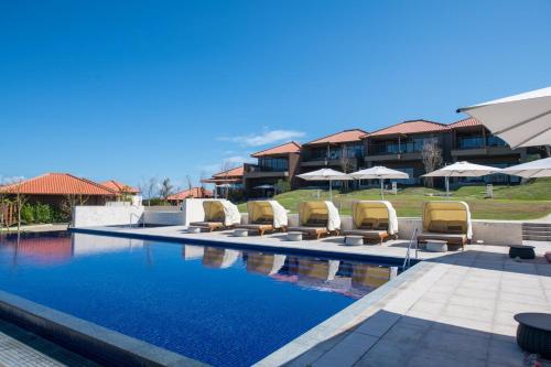 a swimming pool with lounge chairs and umbrellas at THE HIRAMATSU HOTELS & RESORTS GINOZA OKINAWA in Ginoza