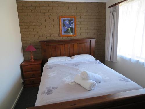 a bedroom with a bed with two towels on it at Warrnambool Motel and Holiday Park in Warrnambool