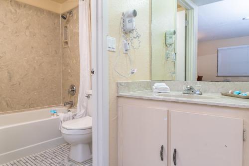 a bathroom with a toilet and a phone on the wall at Sevilla Inn Kissimmee- Near Disney in Kissimmee