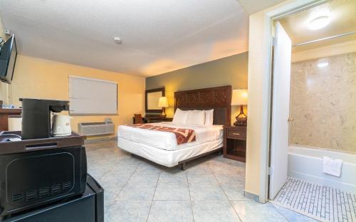 a bedroom with a bed and a tv and a tub at Sevilla Inn Kissimmee- Near Disney in Kissimmee