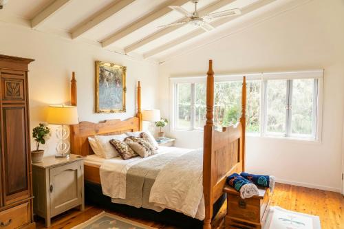 a bedroom with a bed with a wooden frame and windows at Wyndover Mountain Retreat in Beechmont