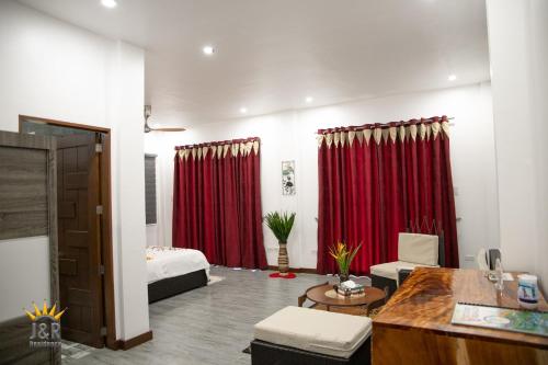 a room with red curtains and a bed and a desk at J&R Residence in Anda