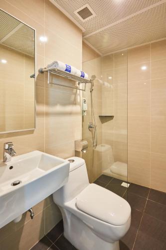a bathroom with a toilet and a sink and a shower at ibis budget Singapore Emerald in Singapore