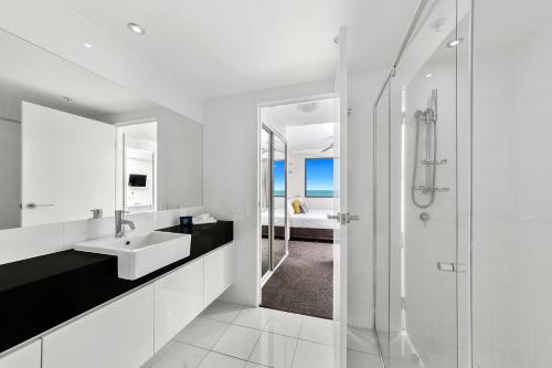 a white bathroom with a sink and a shower at Beach on Sixth in Maroochydore