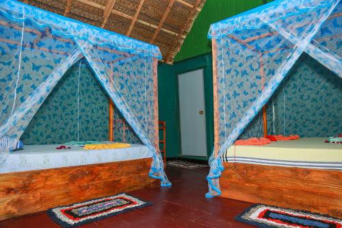 two beds in a room with blue drapes at Lake Face Cabana in Tissamaharama