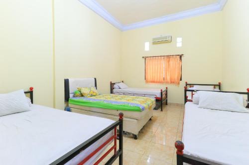 pokój z 3 łóżkami i oknem w obiekcie Hotel Mutiara Khadijah w mieście Sudiang