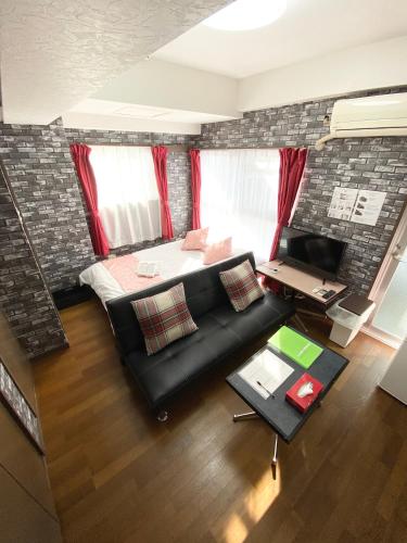 a living room with a black couch and a desk at La Foret Fujimi in Hiroshima