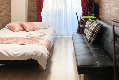 a bedroom with a bed and a leather couch at La Foret Fujimi in Hiroshima