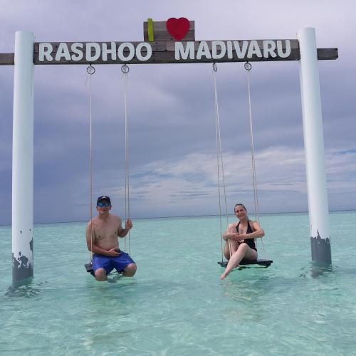 a man and a woman sitting on swings in the ocean at Ras Rana Lodge in Rasdu