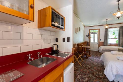 a kitchen with a sink and a room with a bed at Settlers Cottage Motel in Arrowtown
