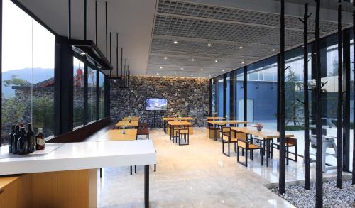 a restaurant with tables and chairs and large windows at The Rock Hotel in Lijiang