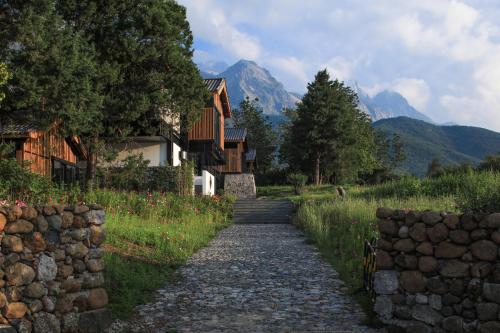 a stone path leading to a house with mountains in the background at The Rock Hotel in Lijiang