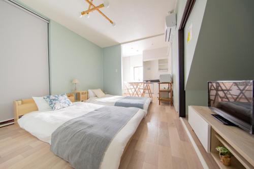 a bedroom with two beds and a television in it at Gummi 駅徒歩12分 USJ電車1駅 EXPOシャトルバス2駅 梅田4駅 in Osaka
