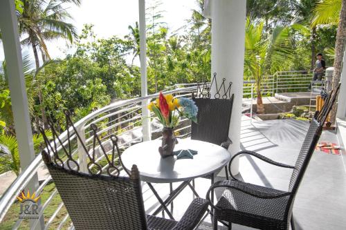 a table and chairs on a porch with a vase of flowers at J&R Residence in Anda