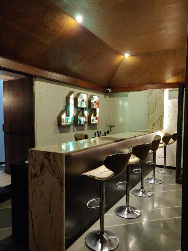 a bar with four stools in a room at Nasiklub in Nashik