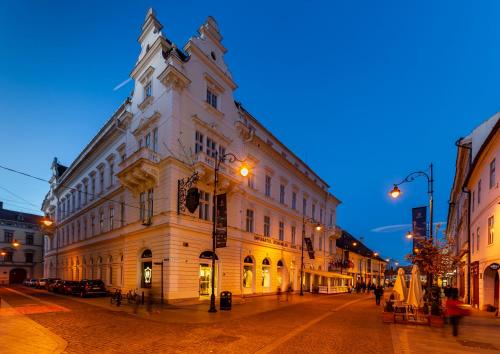 a large white building on a city street at night at Hotel Imparatul Romanilor Hotel & SPA in Sibiu