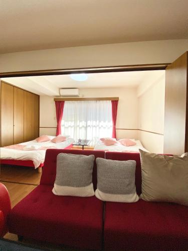 a room with two beds and a red couch at Laforet Tokaichi in Hiroshima