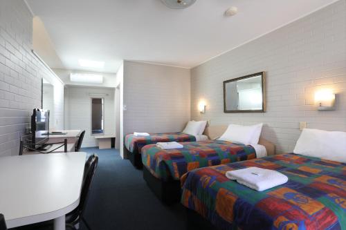 a hotel room with two beds and a table at Econo Lodge Gateway Tamworth in Tamworth