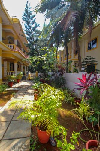 a courtyard of a building with palm trees and plants at Primavera Holiday Homes-FAMILY RUN GOAN GUEST HOUSE in Candolim