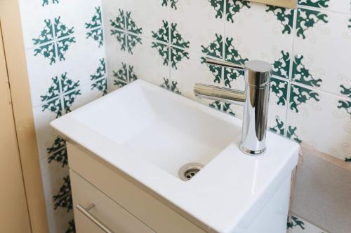 a white sink in a bathroom with green and white tiles at Tropical Loft with View in Volos