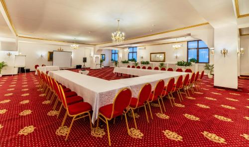 a conference room with a long table and red chairs at Hotel Imparatul Romanilor Hotel & SPA in Sibiu