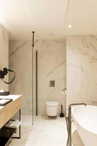 a bathroom with a tub and a toilet and a sink at Corsendonk Turnova in Turnhout