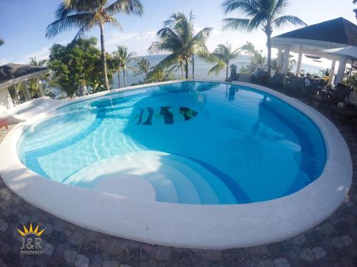 a large blue swimming pool with palm trees in the background at J&R Residence in Anda