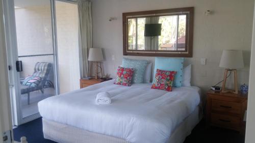 um quarto com uma grande cama branca e um espelho em Apollo Luxury Apartments em Merimbula