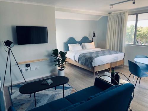 a bedroom with a bed and a blue couch at CURIOCITY Green Point in Cape Town