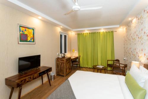 1 dormitorio con cama, TV y cortina verde en The G Snoozebox, en Udaipur