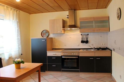 een keuken met zwarte apparatuur en een houten tafel bij Ferienwohnung Jasmin in Schönau bei Heidelberg Fewo 1 mit Terrasse in Schönau