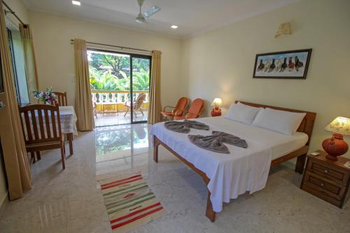a bedroom with a bed and chairs and a balcony at Primavera Holiday Homes in Candolim