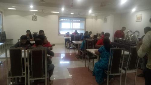 a group of people sitting at tables in a room at Hotel Milam Inn in Almora