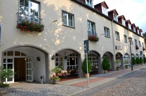 a white building with arches and flowers on a street at Hotel Landhaus Wörlitzer Hof in Oranienbaum-Wörlitz