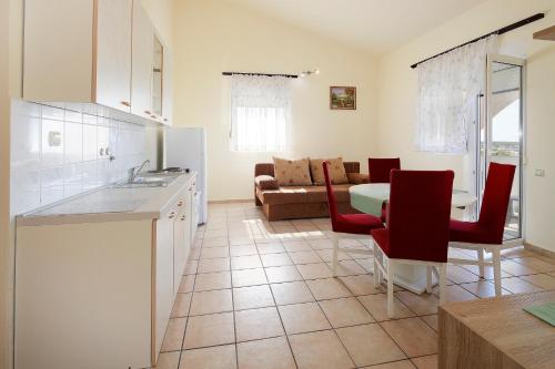cocina y sala de estar con mesa y sillas rojas en Apartments Matin, en Novalja