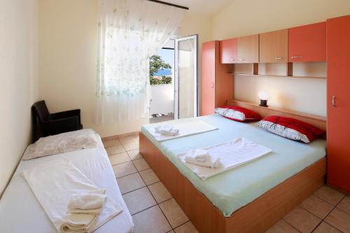 a bedroom with two beds with red and white at Apartments Matin in Novalja