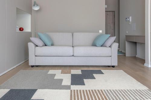 a living room with a white couch with blue pillows at Mint Studio in Druskininkai