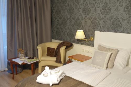 a hotel room with a bed and a chair at Villa Bucher - Metnitztalerhof in Friesach