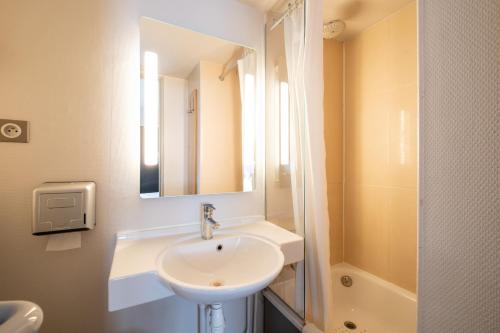 a white bathroom with a sink and a mirror at B&B HOTEL Lille Seclin in Seclin